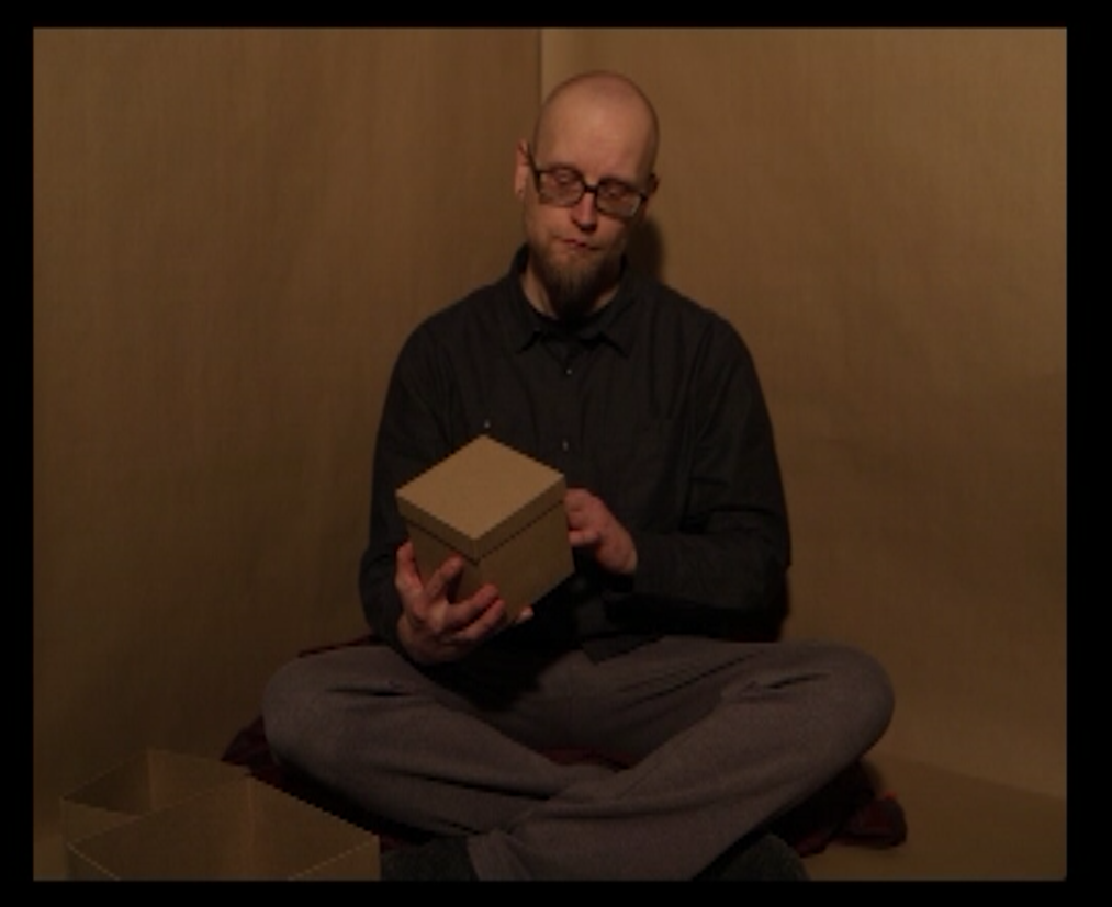 A human sitting in a box is looking at a box.